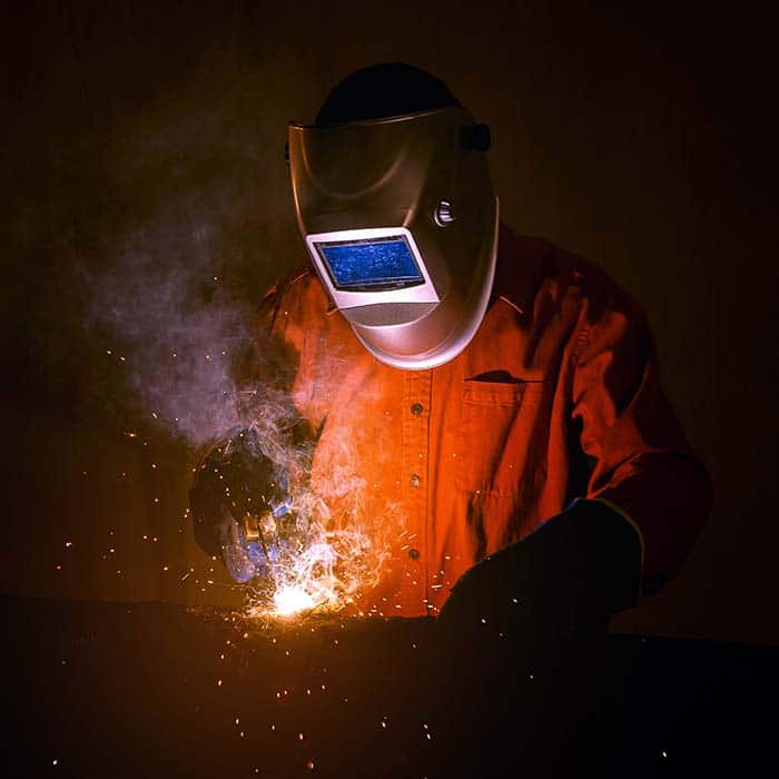 A welder wearing a mask welding metal
